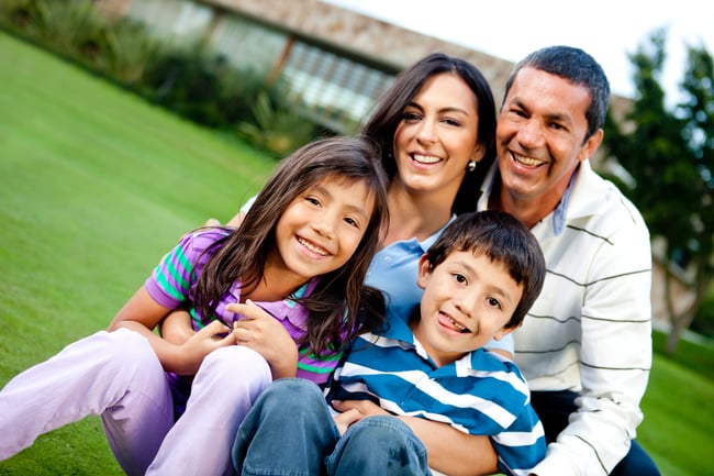 Happy family outdoors with a house at the background