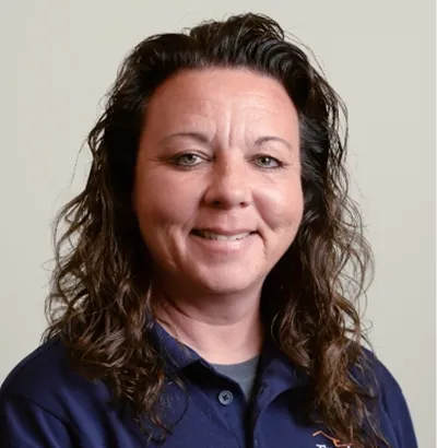 Smiling woman wearing a navy Thrasher Pest Control polo shirt against a plain background