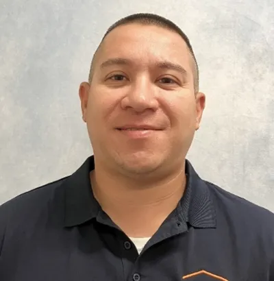 Smiling man in navy polo with Thrasher Pest Control logo on chest against a pale textured background