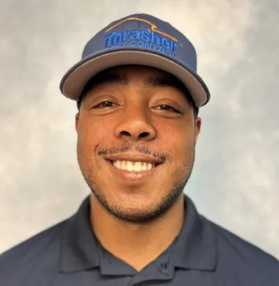 Smiling man wearing Thrasher Pest Control cap and navy polo with company logo.