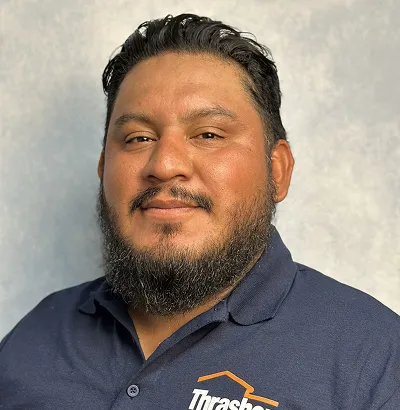 Bearded man wearing navy Thrasher Pest Control polo, close-up portrait with a slight smile